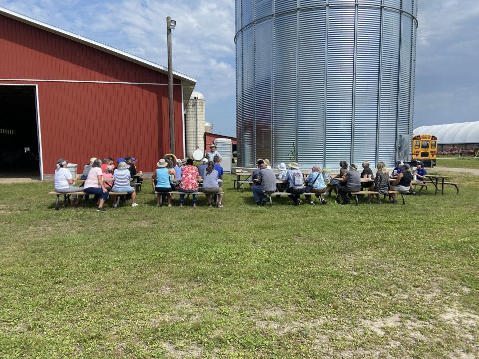 image of farm crawl participants sitting on picnic tables outside of a farm building