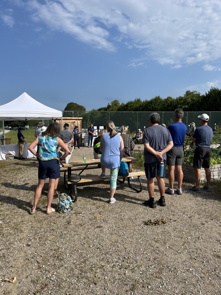 participants are gathered around staff at the community garden for a presentation