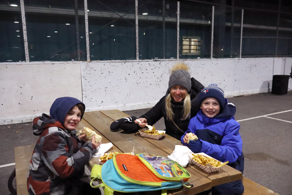 young mom with their two children having a snack at a picnic table in the Perkinsfield Pavilion