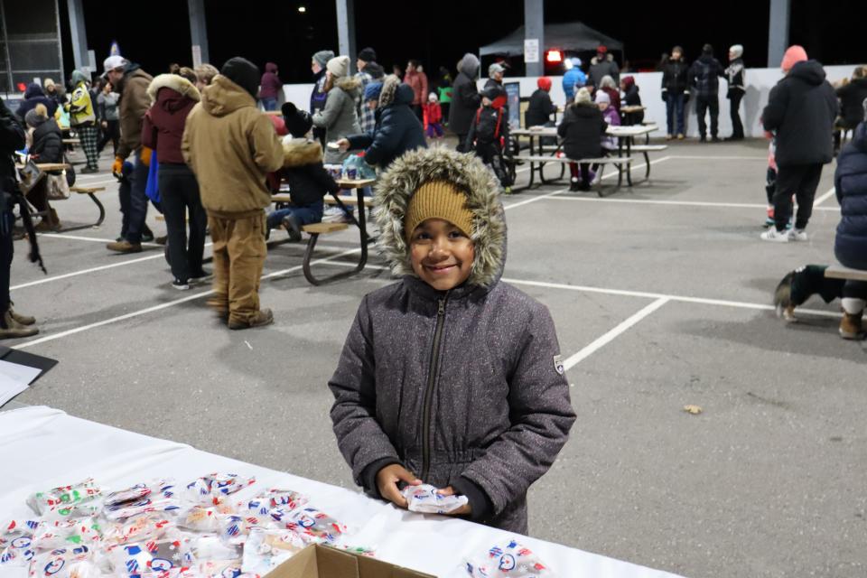 young child getting a cookie from volunteers