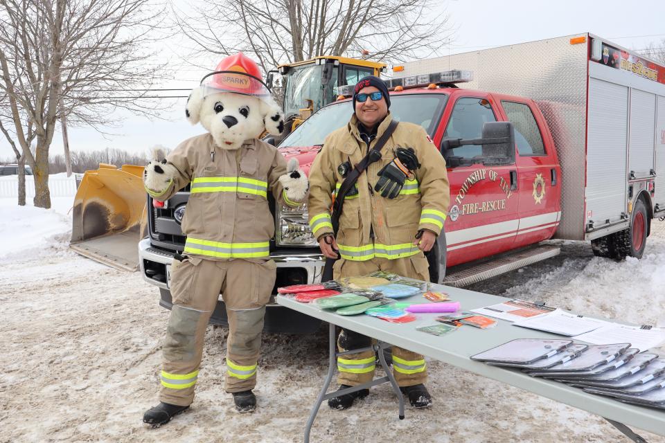 Tiny firefighter and Sparky the dog standing in front of a firetruck