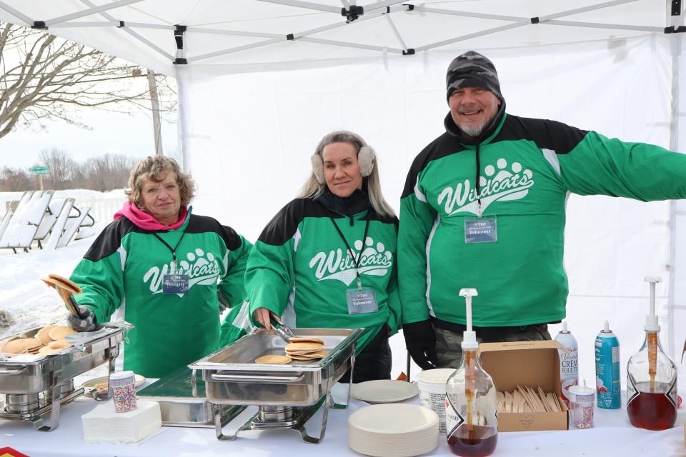 Three volunteers all dressed in green jerseys at the pancake station