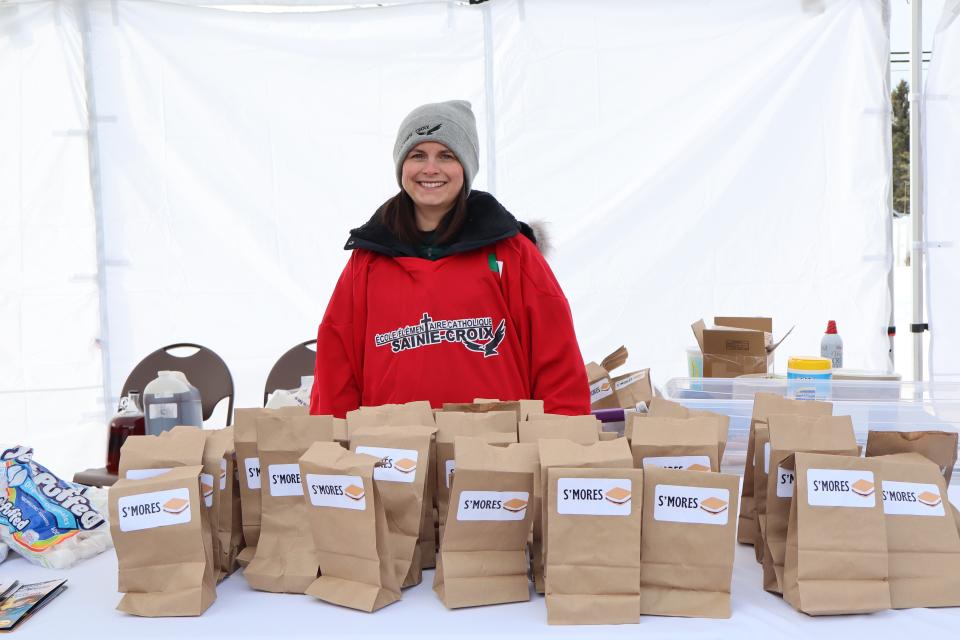 volunteer at the smores table with a table of pre-made kits in brown paper bags