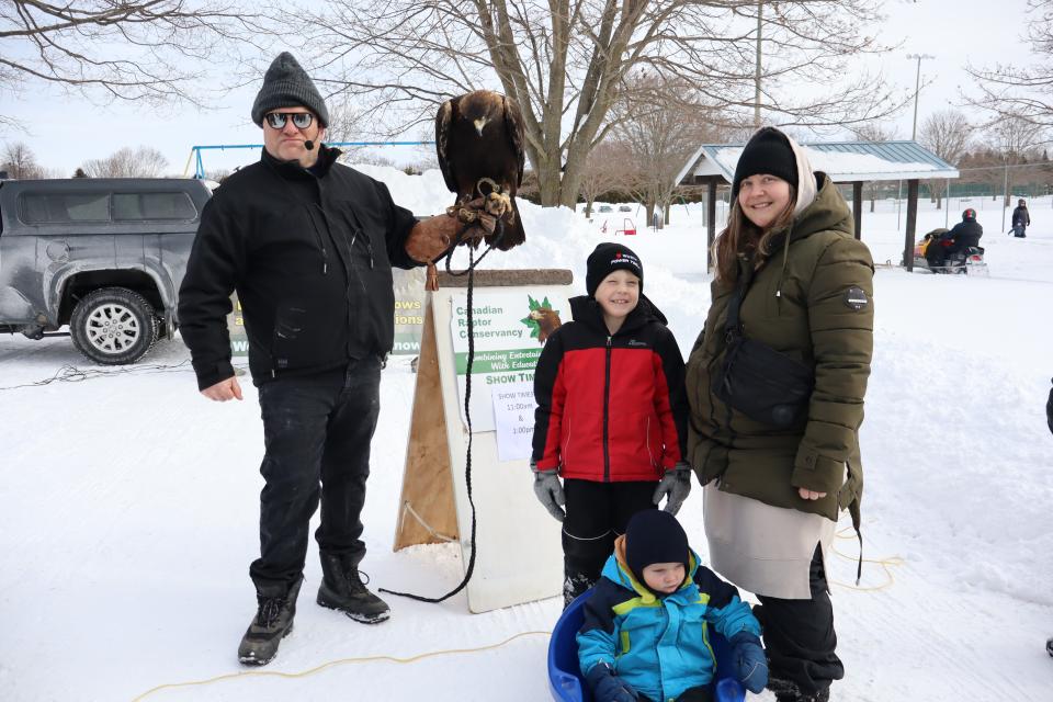 young family posing with a raptor bird and their handler