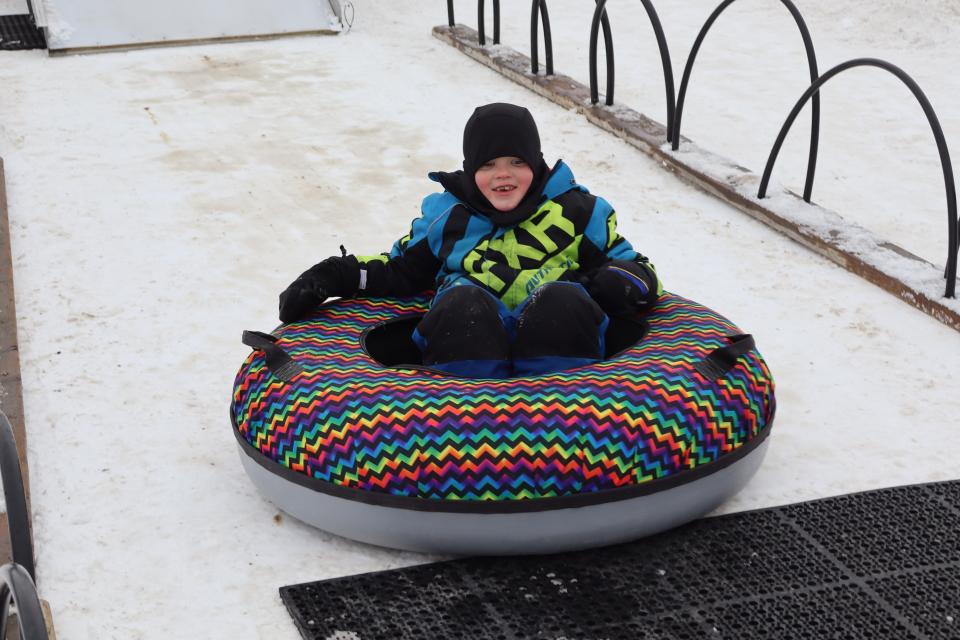 young boy coming down the mobile snow tube hill