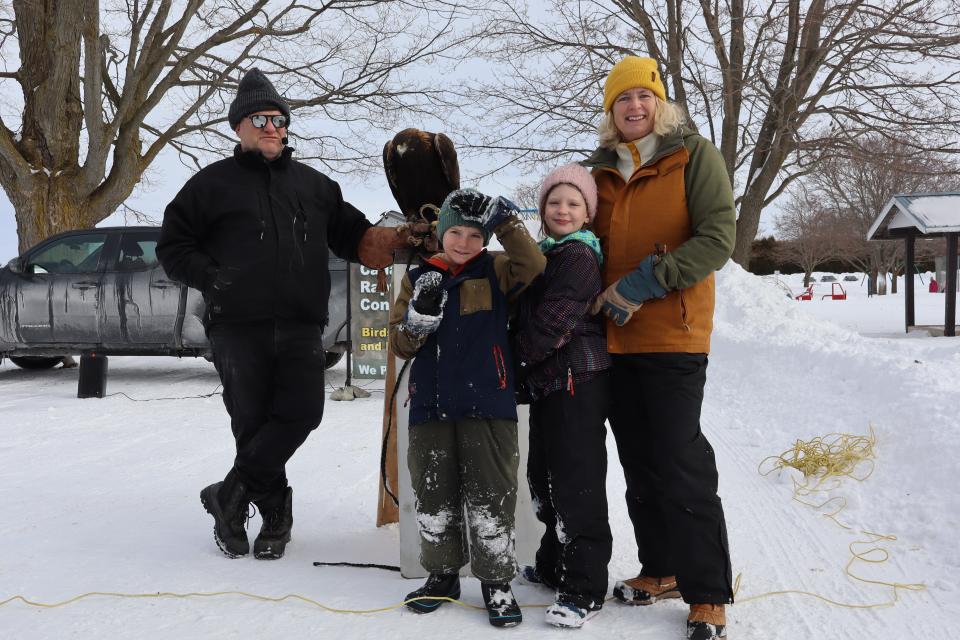 young family posing with a raptor bird and their handler