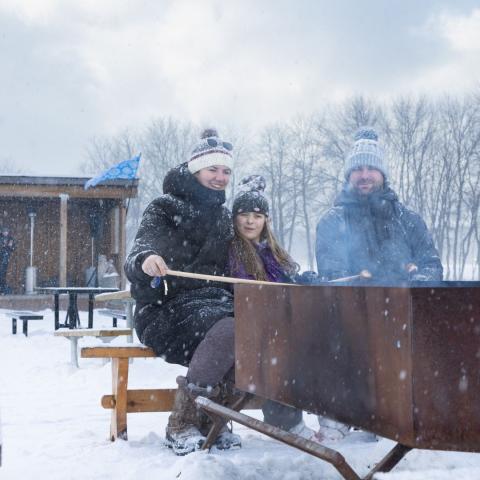 young family roasting food on the fire